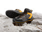 Zwei Paar schwarze Wanderschuhe mit gelben Details auf einem felsigen Untergrund
