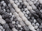 Grauer und weißer Teppich mit Pompons.