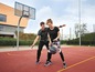 Zwei Personen spielen Basketball auf einem Außenplatz.