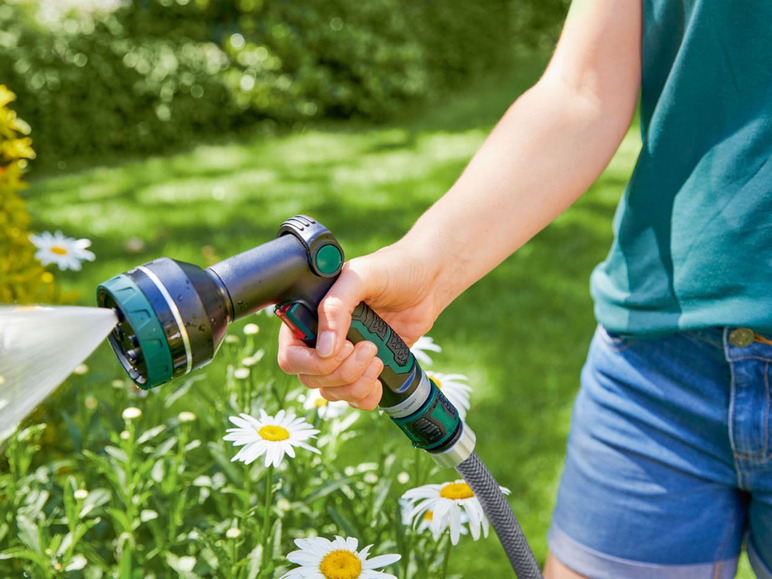 Eine Person gießt Blumen im Garten mit einem Gardena Schlauch und einer Spritze.