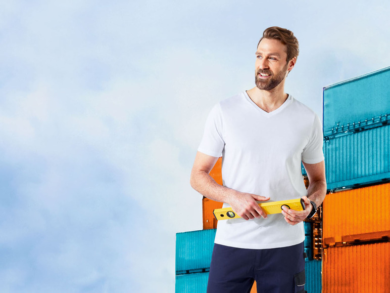 Ein Mann mit einem weißen T-Shirt und einer Wasserwaage vor einem Stapel Container