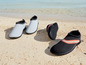 Schwarze und graue Wasserschuhe am Strand.