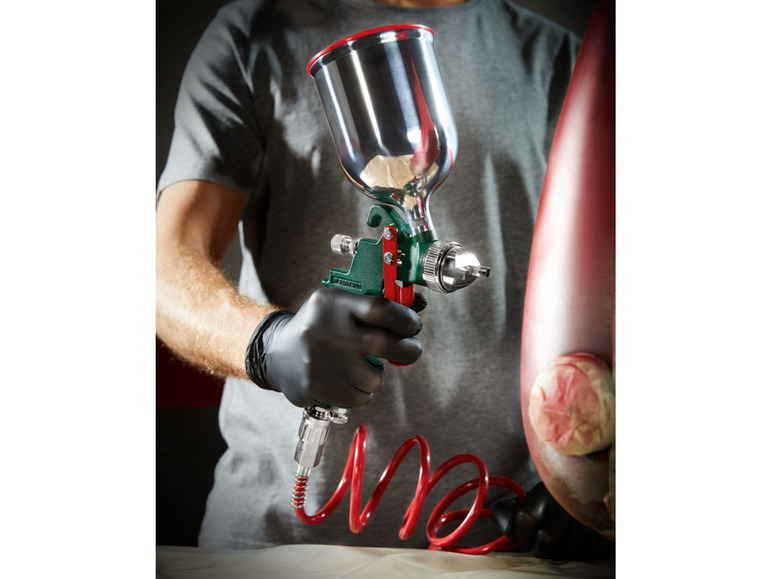 Eine Person sprüht ein Objekt mit einer Spritzpistole an.