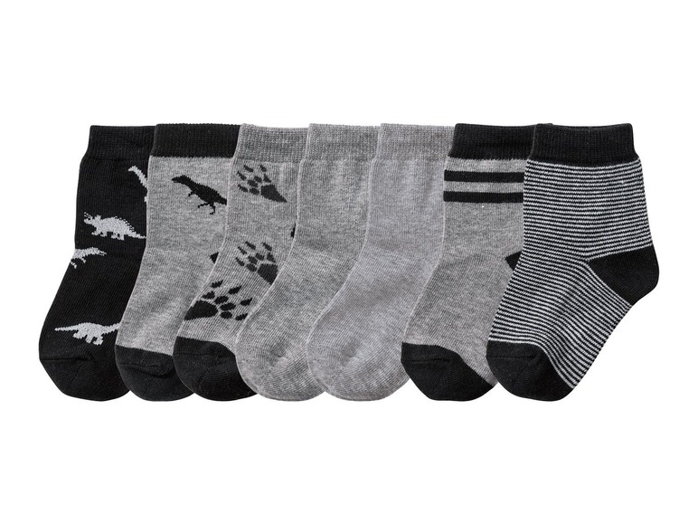 Sechs Paar Socken mit Dinosauriern, Fußabdrücken und Streifen.
