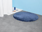 Eine runde, blaue Badematte im Badezimmer.