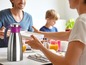 Eine Thermoskanne für Kaffee oder Tee auf dem Tisch mit einer Familie beim Frühstück.