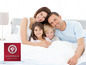 Eine Familie lächelt im Bett mit Sannwald Bettwäsche.