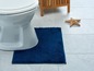 Eine Toilette mit einem blauen Badezimmerteppich in einem Badezimmer.