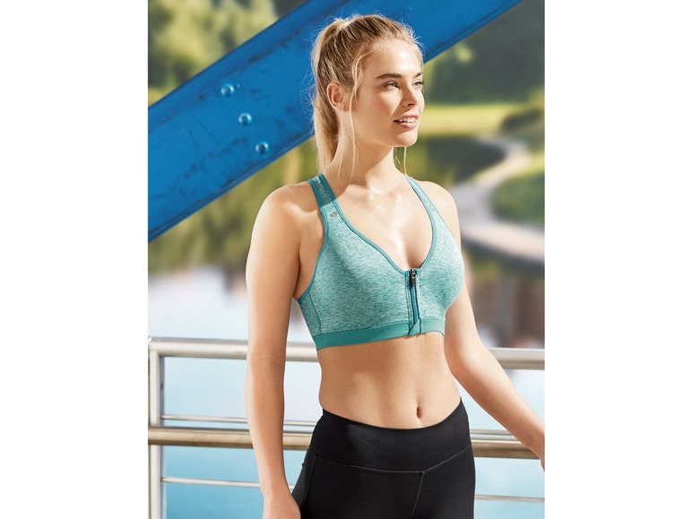 Eine Frau trägt einen grünen Sport-BH und schwarze Leggings.