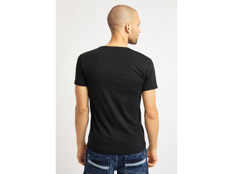 Mann in einem schwarzen T-Shirt und blauen Jeans.