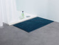 Ein dunkelblauer Badezimmerteppich in einem Badezimmer.