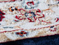 Detail eines Teppichs mit einem geometrischen Muster in Rot-, Blau- und Beigetönen.