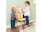 Zwei Kinder spielen mit einer Holzspielküche mit Backofen und Kaffeemaschine.