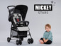 Ein schwarzer Mickey Mouse Kinderwagen mit einem Baby, das daneben sitzt.