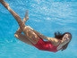 Eine Frau in einem roten Badeanzug schwimmt unter Wasser.