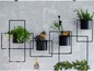 Schwarzes Metallwandregal mit Töpfen und Pflanzen.