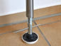 Ein Metallpfosten mit Gewinde und einem schwarzen Fuß auf einem Fliesenboden.