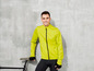 Mann in einer gelben Fahrradjacke mit schwarzer Fahrradhose und einem Fahrrad.