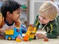 Zwei Kinder spielen mit LEGO DUPLO Baufahrzeugen.