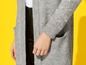 Ein grauer Strickcardigan mit Perlen an den Ärmeln.