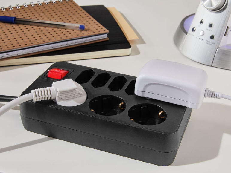Eine schwarze Steckdosenleiste mit einem weißen Stecker und einem weißen Adapter.
