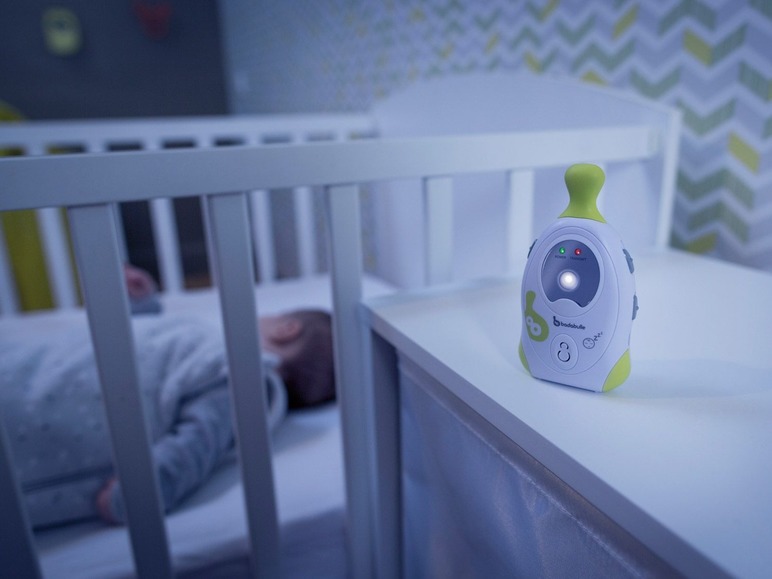 Ein Babyphone von Babymoov neben einem schlafenden Baby im Bettchen.