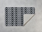 Ein grauer und schwarzer Teppich mit Chevron-Muster