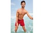 Mann in roten Badehosen im Meer.