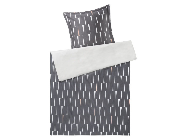 Ein grauer Bettbezug mit weißen Dreiecken und ein Kissen mit rosafarbenen Akzenten.