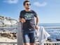 Mann in einem T-Shirt mit Strandprint und Shorts.