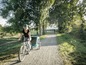Eine Frau fährt mit einem Fahrradanhänger auf einem befestigten Weg.