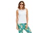 Eine Frau trägt ein weißes Tanktop mit Spitze und eine Hose mit tropischem Muster.