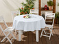 Weißer Tischdecke auf einem runden Tisch mit vier weißen Klappstühlen.