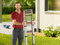 Mann mit einer Teleskopleiter im Garten.