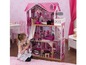 Ein rosa Puppenhaus mit einem Mädchen, das damit spielt.