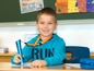 Ein Junge in einem blauen Pullover benutzt einen blauen Stift im Klassenzimmer.