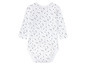 Ein weißer Baby-Body mit schwarzen Punkten.