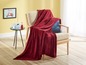 Eine rote Wolldecke auf einem Stuhl in einem hellen Wohnzimmer.
