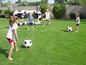 Kinder spielen Fußball auf dem Rasen mit einem aufblasbaren Tor.