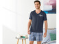Mann in blauem T-Shirt mit 'California'-Aufdruck und karierten Schlafshorts.