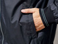 Eine schwarze Windjacke mit einem blauen Streifen am Ärmel.
