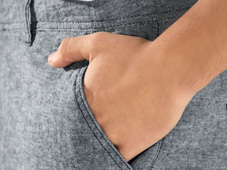 Eine Hand in der Tasche einer grauen Hose.