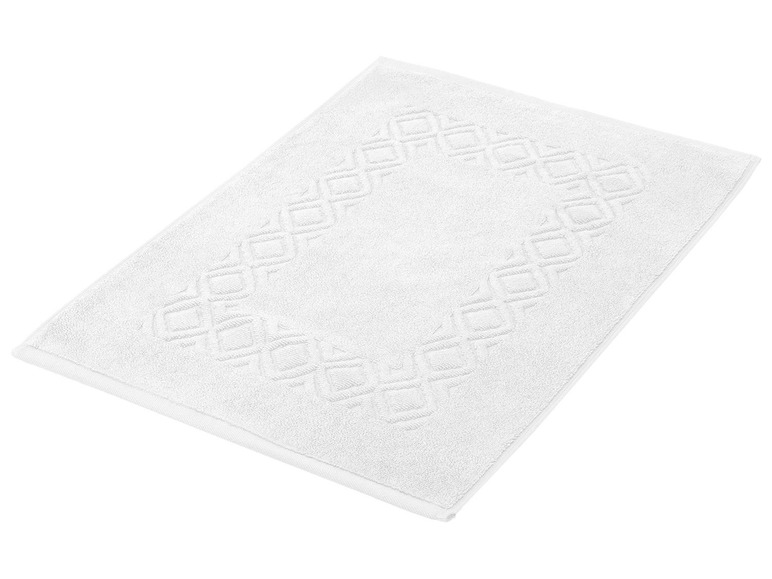 Ein weißes Badezimmer-Teppich mit geometrischem Muster.