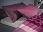 Ein rosafarbenes Bettbezug-Set mit geometrischem Muster und zwei passenden Kissen.