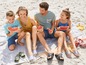 Eine Familie genießt Wassermelone am Strand und trägt bequeme Slipper.