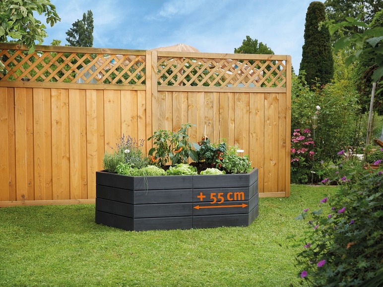 Ein schwarzer, rechteckiger Pflanzenkasten mit Gemüse und Kräutern im Garten.