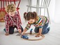 Zwei Kinder spielen mit einer Holzeisenbahn und einem Polizeiauto.