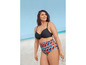 Eine Frau trägt einen schwarzen Bikini-Oberteil und eine High-Waist-Hose mit geometrischem Muster am Strand.