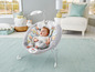 Ein Baby sitzt in einem Fisher-Price Schaukelstuhl mit Muster.