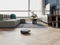 Ein Roboterstaubsauger reinigt einen Holzboden in einem modernen Wohnzimmer.